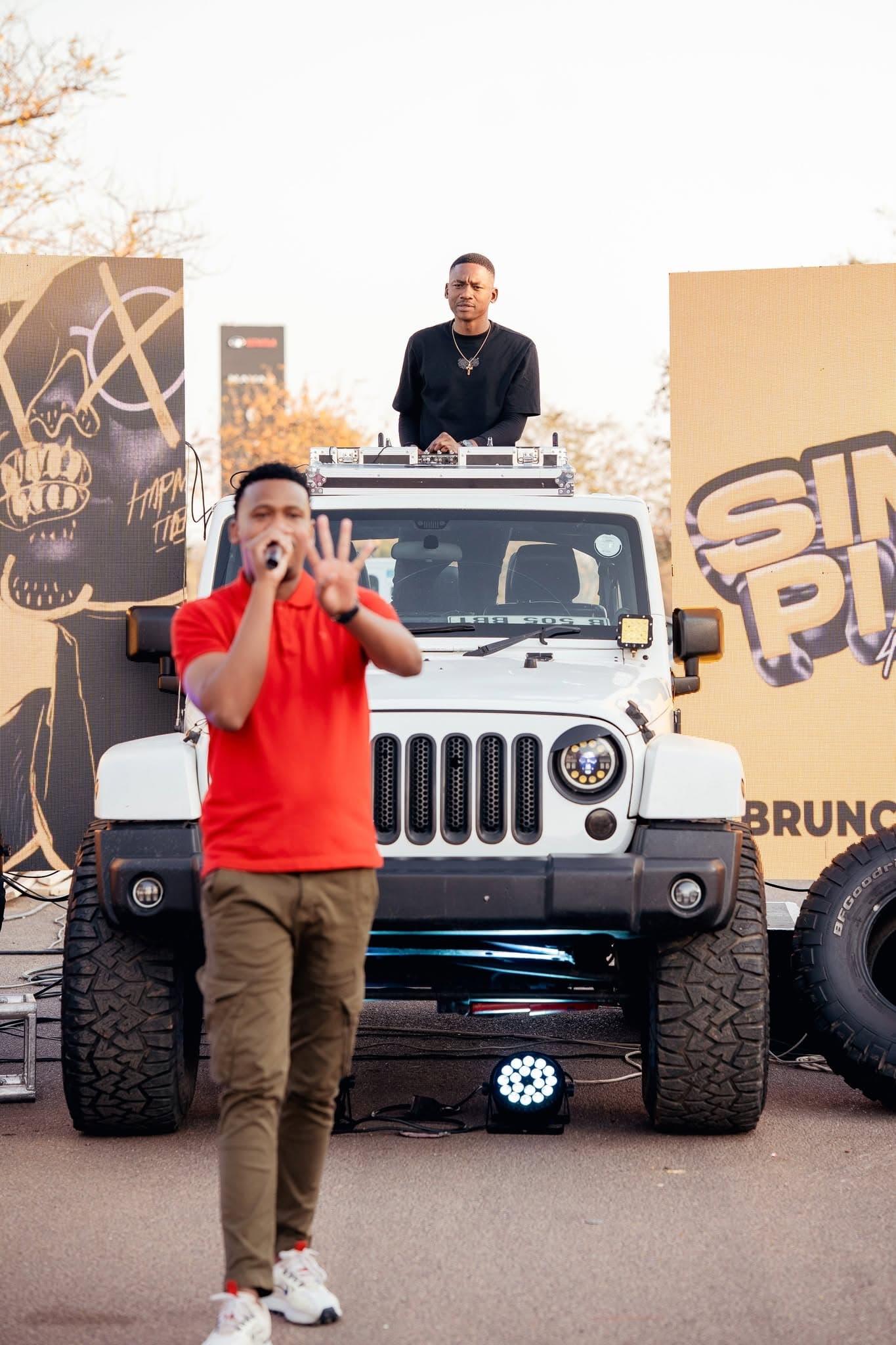 Host on the microphone standing on a Jeep at a Simply Piano roadshow