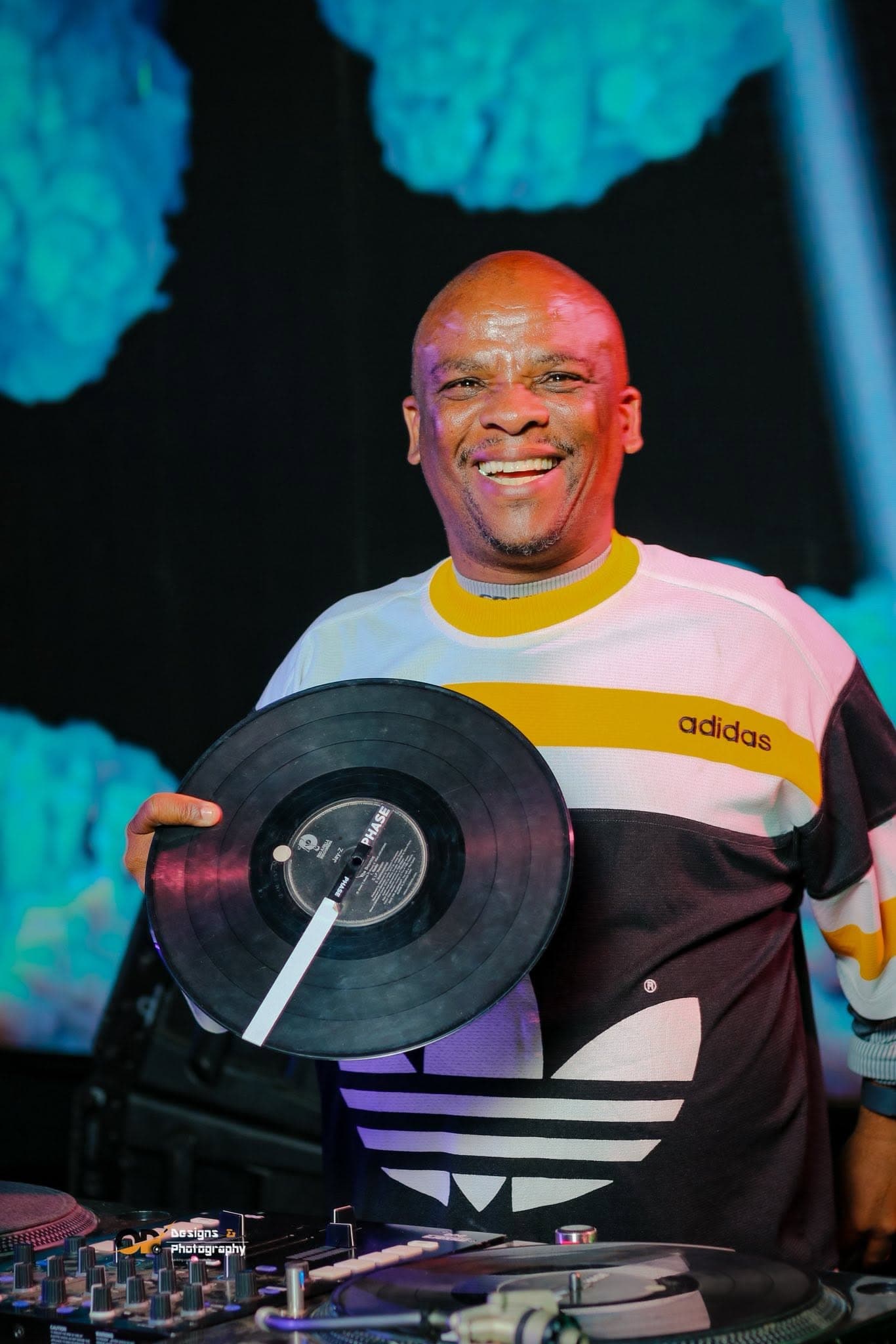 DJ holding a vinyl record behind the decks