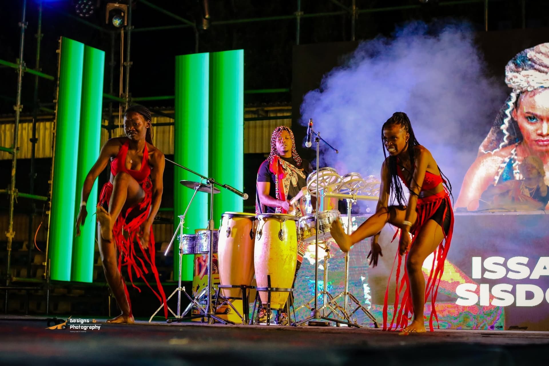 Drummers performing under green stage lighting