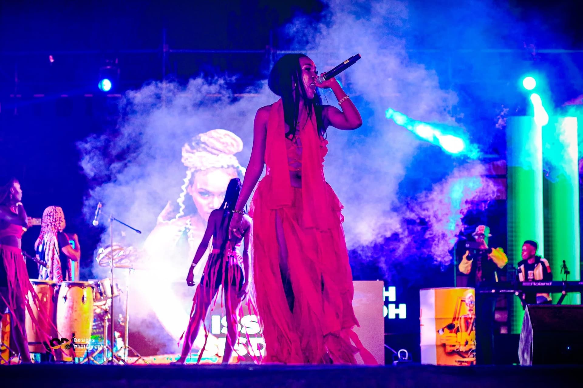 Singer performing on stage in pink-lit smoke at a Simply Piano event